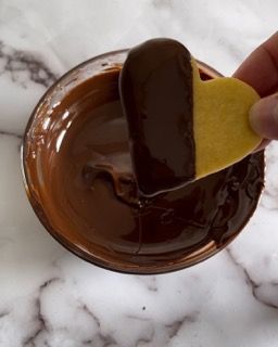 Una persona sta immergendo un biscotto a forma di cuore nel cioccolato