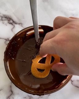 Una persona sta immergendo una zucca nel cioccolato