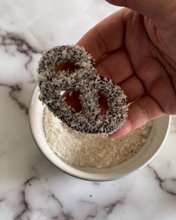 Una persona tiene in mano una ciambella sopra una ciotola di riso.