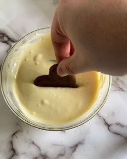 Una persona sta immergendo un biscotto a forma di cuore in una ciotola di yogurt.