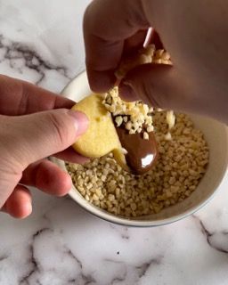 Una persona sta immergendo un biscotto in una ciotola di noci
