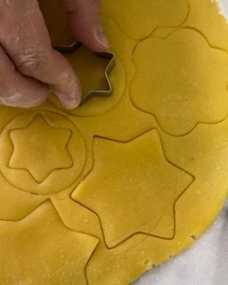 Una persona sta usando un tagliabiscotti per ritagliare delle forme su un pezzo di pasta.
