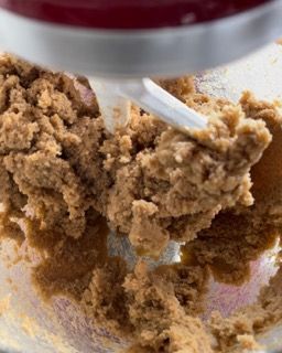 Un mixer sta mescolando una sostanza marrone in una ciotola di vetro.