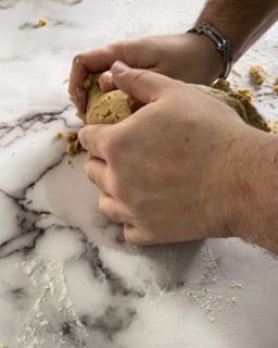 Una persona sta impastando l'impasto su un tavolo di marmo.