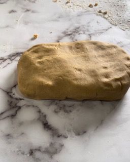 Un pezzo di pasta è appoggiato su un bancone di marmo.