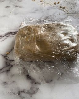 Un pezzo di pasta è avvolto nella pellicola trasparente su un tavolo.