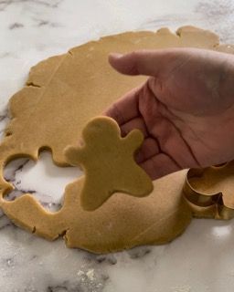 Una persona tiene in mano un biscotto a forma di omino di pan di zenzero.