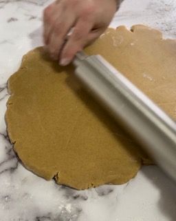 Una persona sta stendendo la pasta con un mattarello su un tavolo.
