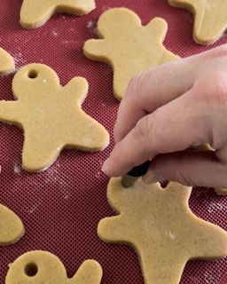 Una persona sta decorando i biscotti di pan di zenzero su un tappetino rosso