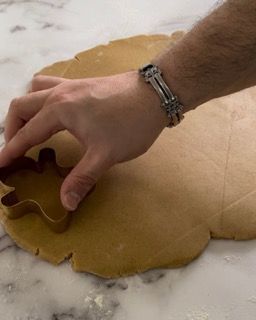 Una persona sta usando un tagliabiscotti su un pezzo di pasta.