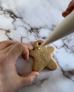 Una persona sta decorando un biscotto a forma di omino di pan di zenzero con la glassa.