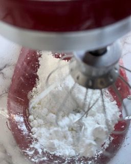 Un mixer sta mescolando lo zucchero a velo in una ciotola.