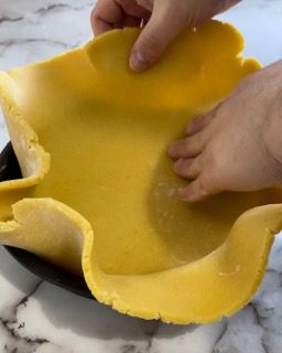 Una persona tiene in mano un pezzo di pasta gialla.