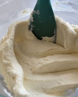 Una spatola verde è in una ciotola di panna montata.