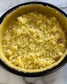 Una pasta per torta con delle briciole dentro è appoggiata su un tavolo.