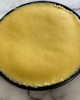 Un primo piano di una salsa gialla su un piatto nero su un tavolo.