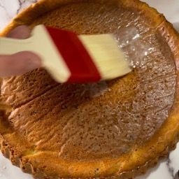 Una persona sta spennellando una torta con un pennello.