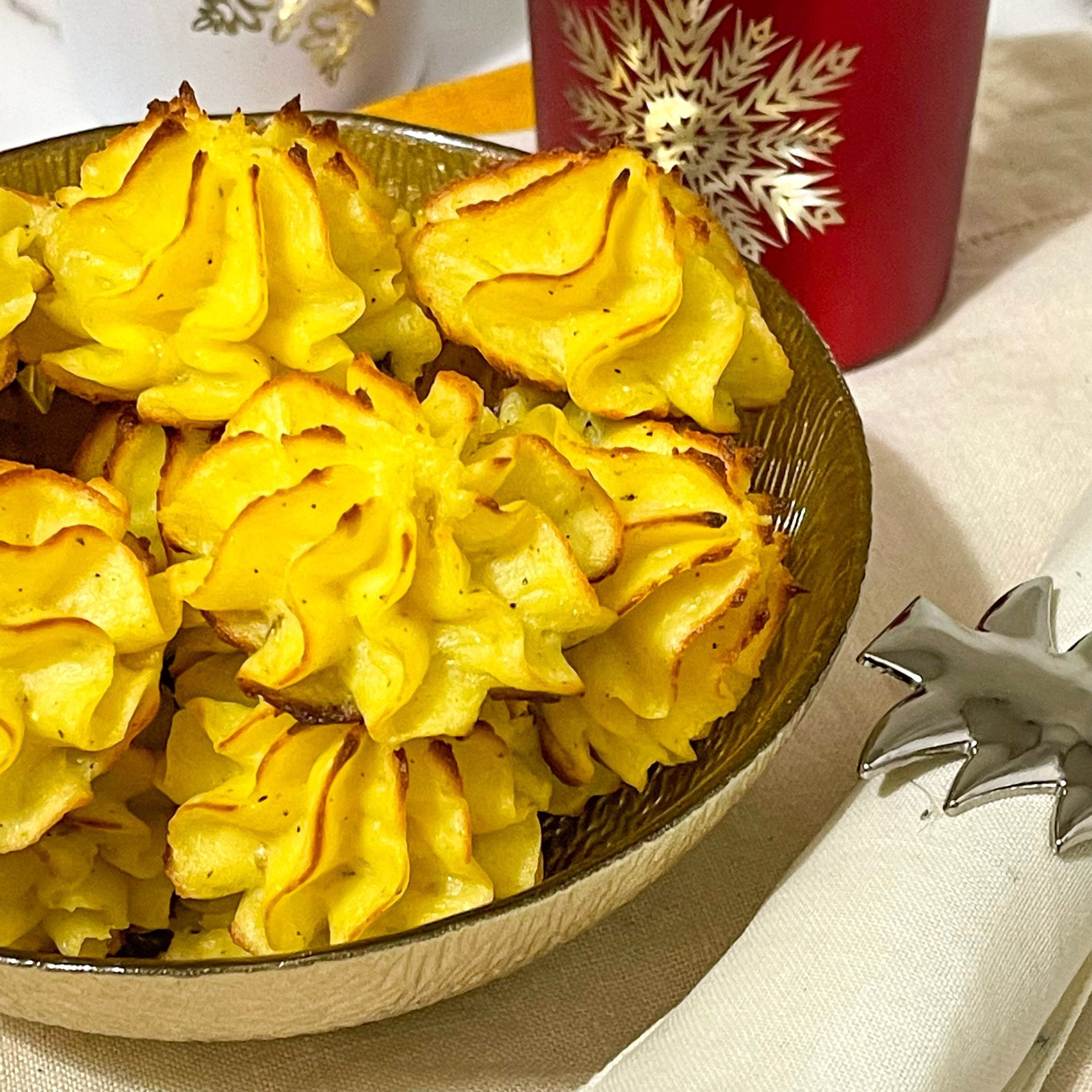 Una ciotola di purè di patate accanto a una tazza rossa con un fiocco di neve sopra