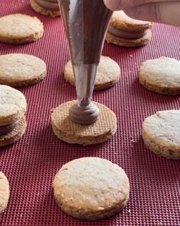 Una persona sta versando il cioccolato su un biscotto con una tasca da pasticcere