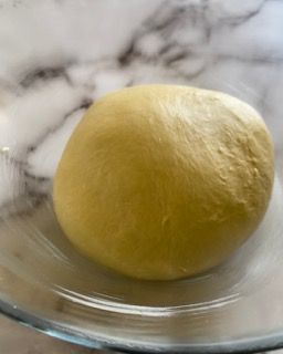 Una palla di pasta è appoggiata su un piatto di vetro.