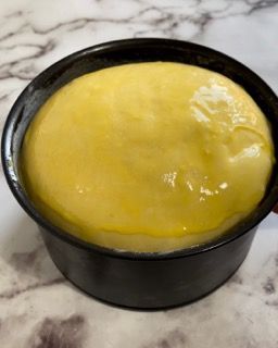 Una ciotola nera piena di salsa gialla su un tavolo.