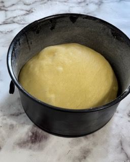 Su un tavolo c'è una ciotola nera piena di liquido giallo.