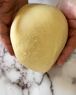 Una persona tiene in mano una palla di pasta.