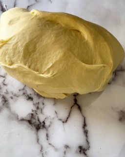 Un grosso pezzo di pasta è appoggiato su una superficie di marmo.