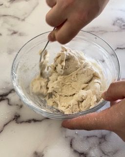 Una persona sta mescolando qualcosa in una ciotola con un cucchiaio.