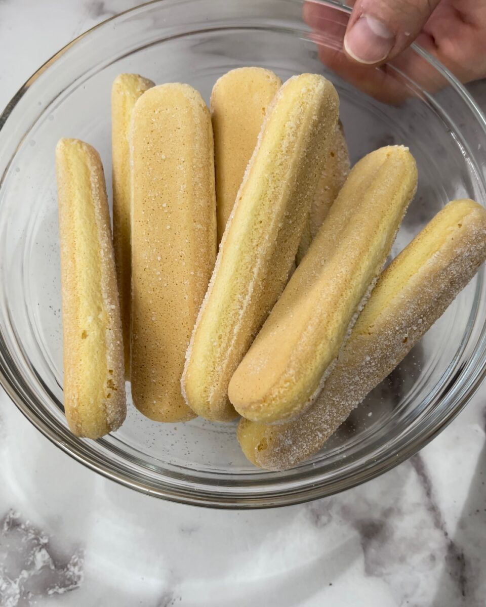 Savoiardi inzuppati velocemente nel caffè espresso per la base del tiramisù.
