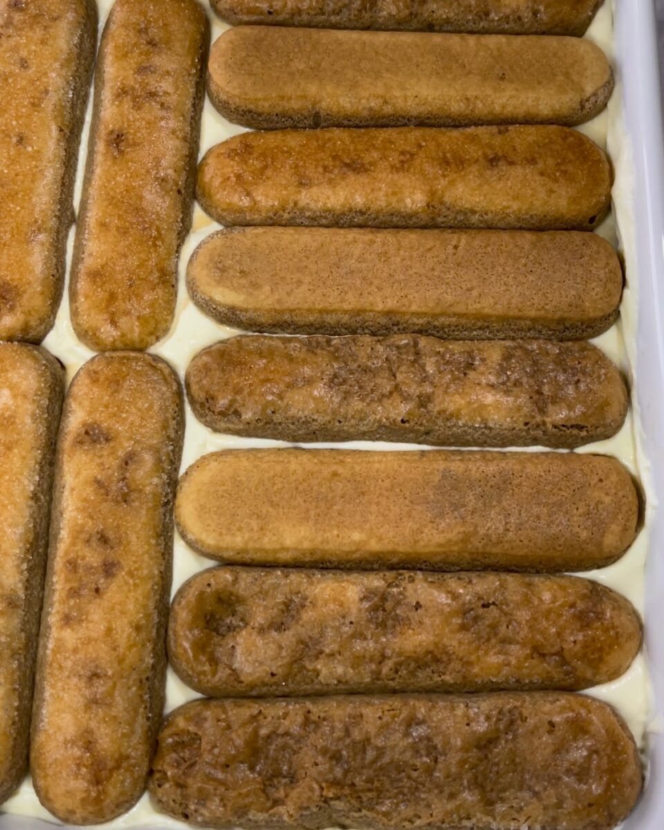 ssemblaggio del tiramisù classico con il secondo strato di crema al mascarpone spalmata sui savoiardi.