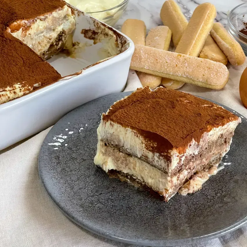 Fetta di tiramisù servita su un piatto, che mostra perfettamente gli strati di savoiardi e crema al mascarpone