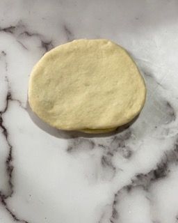 Un pezzo di pasta è appoggiato su una superficie di marmo.