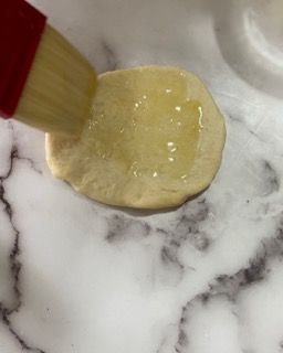 Si usa un pennello per spennellare un pezzo di pasta su una superficie di marmo.