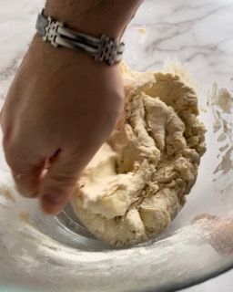 Una persona sta mescolando l'impasto in una ciotola di vetro.