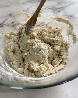 Una ciotola di impasto con un cucchiaio di legno dentro.