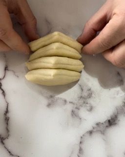 Una persona tiene in mano un pezzo di pasta su una superficie di marmo.