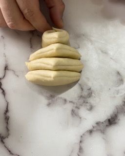 Una persona tiene in mano un pezzo di pasta su una superficie di marmo.