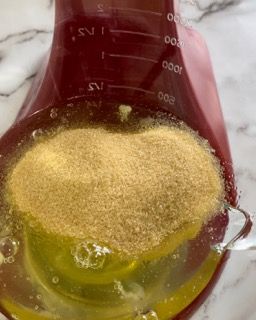 Un misurino pieno di un liquido giallo e di polvere marrone.