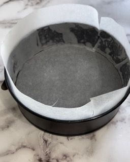 Una tortiera ricoperta di carta oleata è appoggiata su un tavolo.