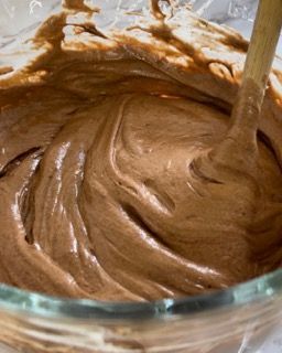 Una ciotola di glassa al cioccolato con un cucchiaio di legno dentro