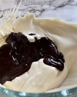 Una ciotola di vetro piena di panna montata e salsa al cioccolato.