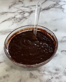 Una ciotola di salsa al cioccolato con un cucchiaio dentro