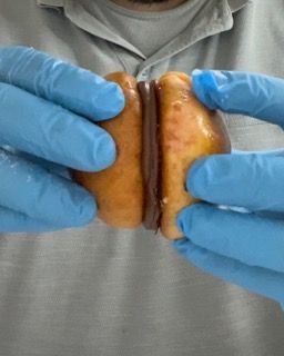 Una persona che indossa guanti blu tiene una ciambella tra le mani