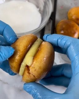 Una persona che indossa guanti blu tiene in mano un panino