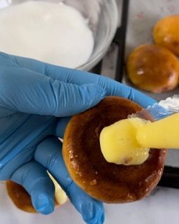 Una persona che indossa guanti blu tiene in mano una ciambella con un cucchiaio dentro