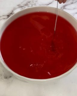 Una persona sta mescolando una ciotola di liquido rosso con un cucchiaio.