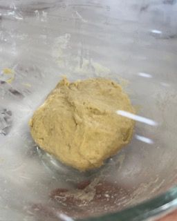 Primo piano di un pezzo di impasto in una ciotola di vetro.