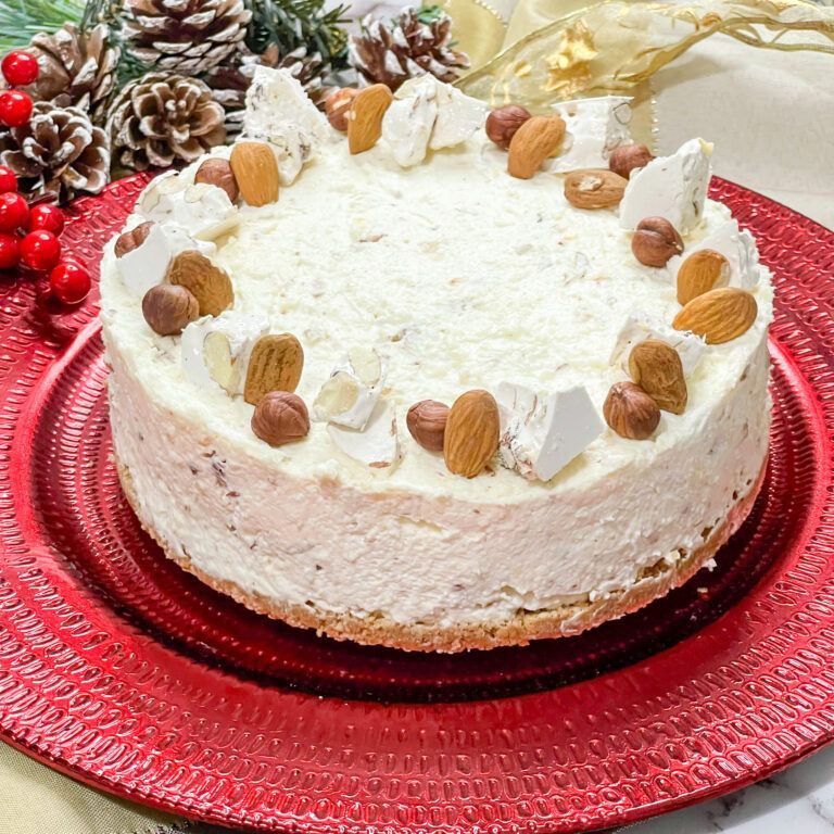 Una torta bianca con sopra delle noci è su un piatto rosso.