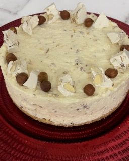 Una cheesecake con noci sopra è su un piatto rosso
